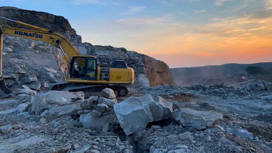 Excavator working in a rocky landscape at sunset, preparing the site for development.